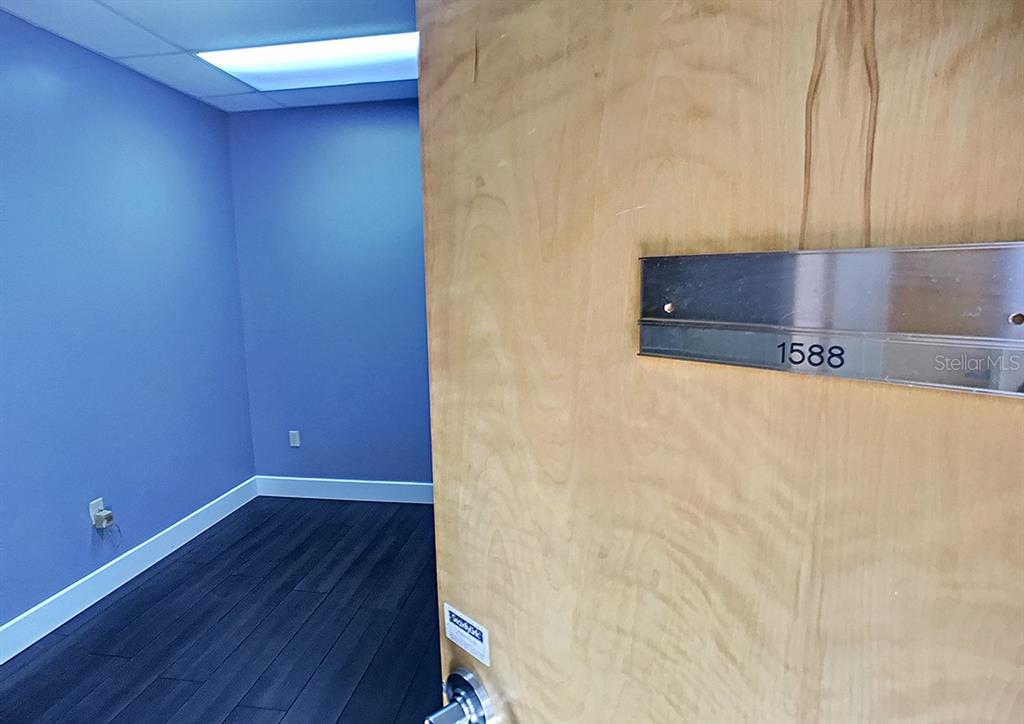 A light wood door with the number 1588 opens into a small, empty office space — 1588 TROPIC PARK DRIVE UNIT 1588, SANFORD, FL