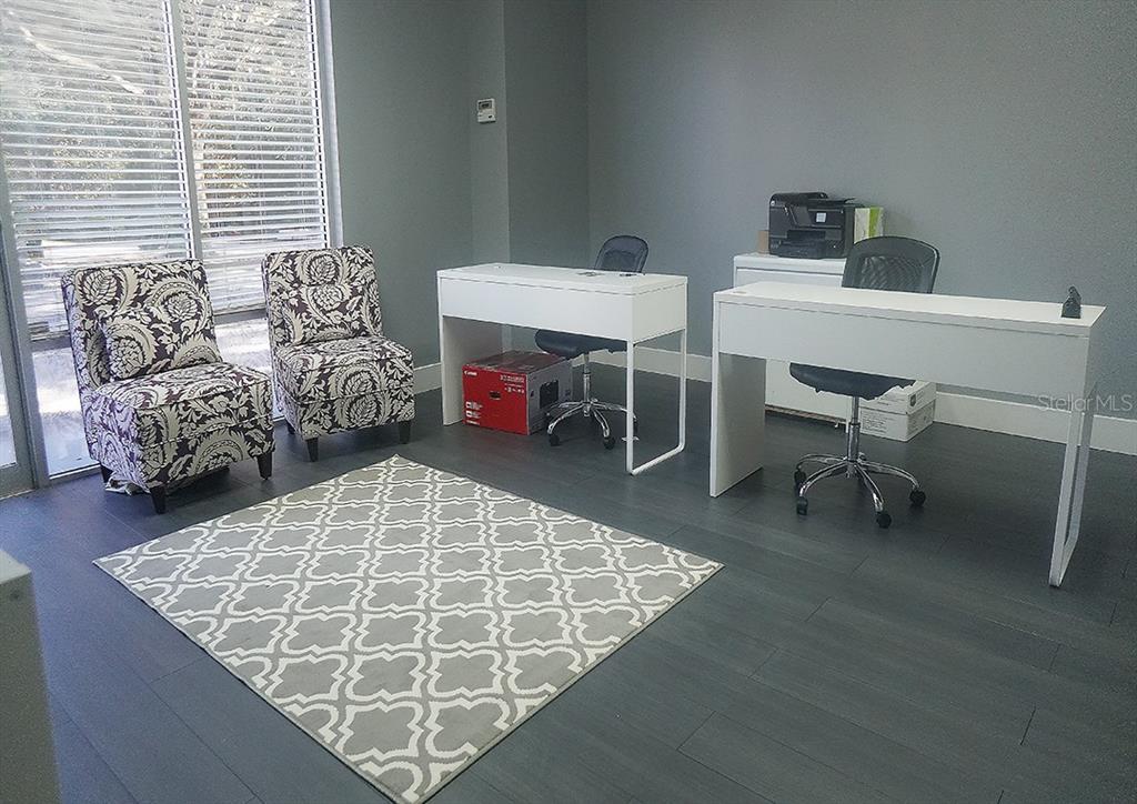An office space features two white desks, two patterned chairs, and a gray area rug — 1588 TROPIC PARK DRIVE UNIT 1588, SANFORD, FL