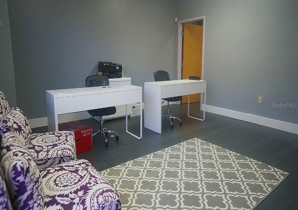 An office space features two white desks, rolling chairs, and purple patterned chairs on flooring — 1588 TROPIC PARK DRIVE UNIT 1588, SANFORD, FL