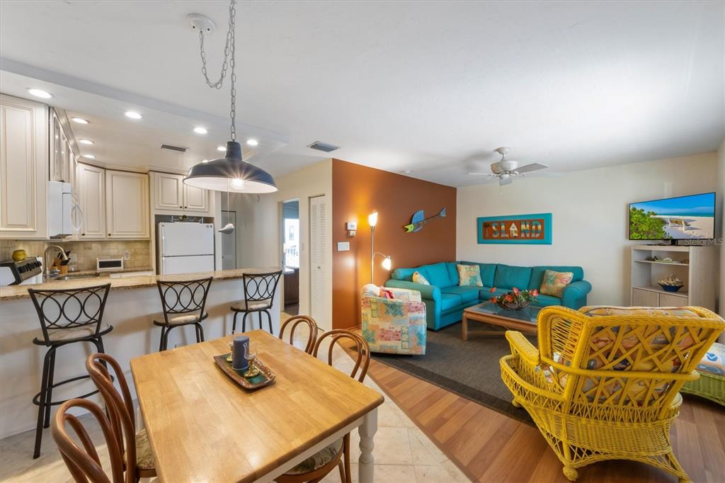 An open-concept living and dining area features a kitchen with bar seating and tile flooring — 117 7TH STREET N UNIT 35, BRADENTON BEACH, FL