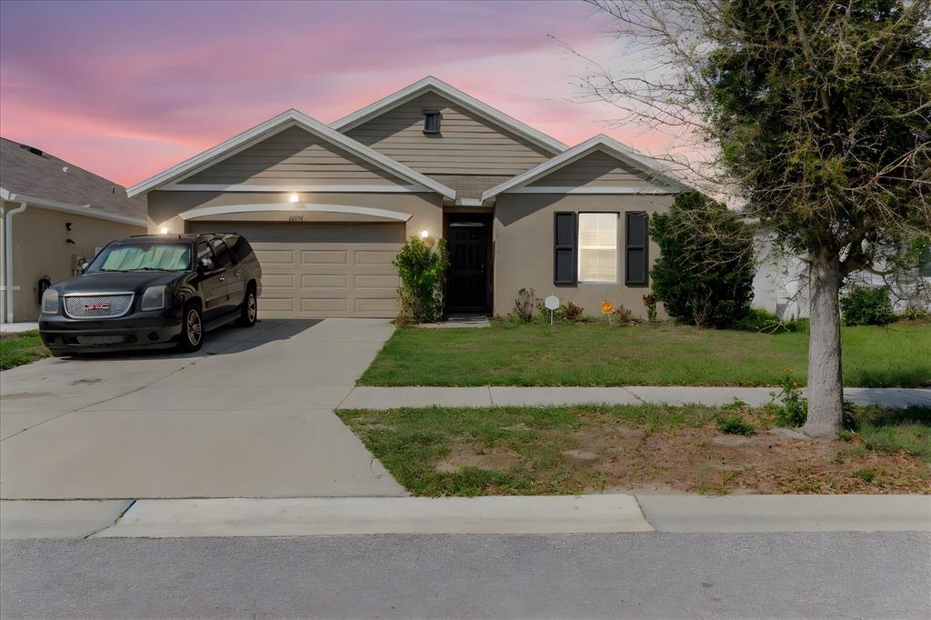 A single-story house with a beige exterior, a two-car garage, and a parked black SUV — 10206 GOLDEN LIGHT COURT, RIVERVIEW, FL