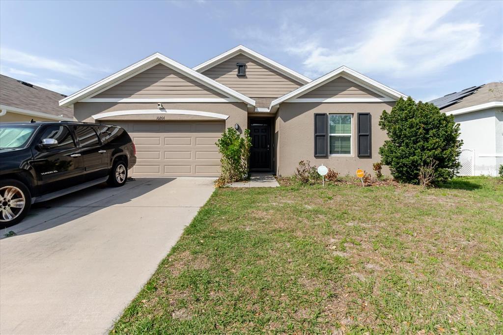A single-story house with a beige stucco exterior, a two-car garage, and a front lawn — 10206 GOLDEN LIGHT COURT, RIVERVIEW, FL
