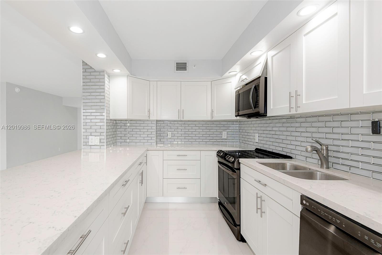 A modern kitchen features white cabinets, quartz countertops, a gray subway tile backsplash, and appliances — 1201 S Ocean Dr # 610N, Hollywood FL 33019, HOLLYWOOD, FL