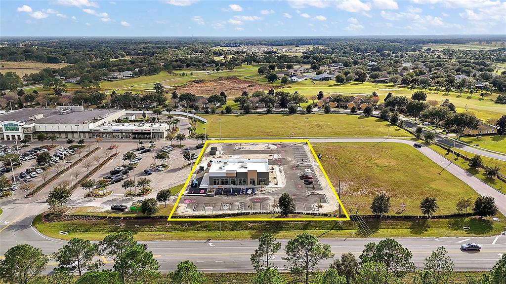 An aerial view shows a newly constructed commercial building surrounded by a parking lot — 24430 STATE ROAD 44, SORRENTO, FL