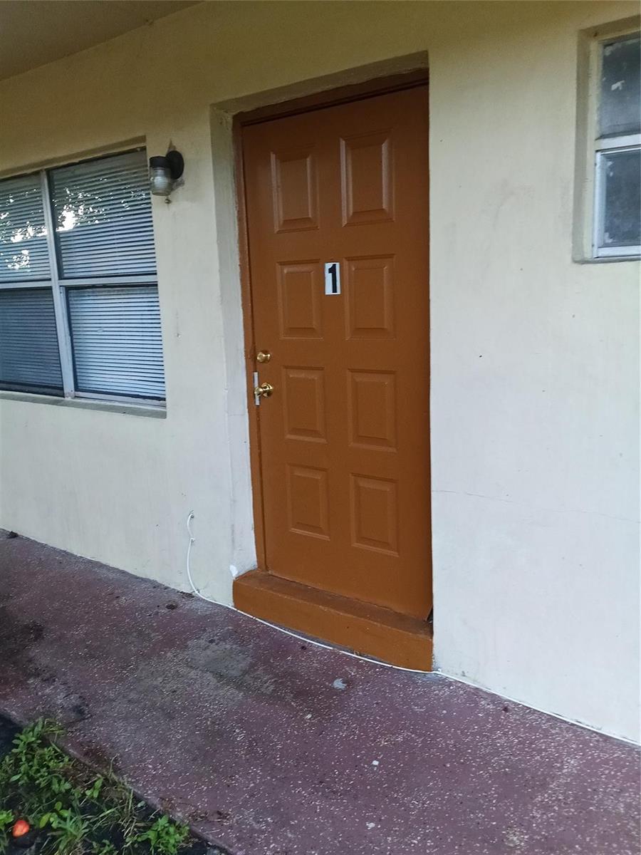 A brown door marked with the number one sits on a concrete walkway — 1845 NW 55th Avenue, Lauderhill FL 33313, LAUDERHILL, FL