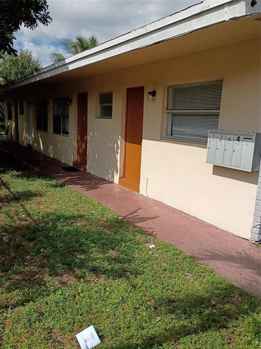 A side view of a single-story apartment building with multiple doors and a mailbox unit — 1845 NW 55th Avenue, Lauderhill FL 33313, LAUDERHILL, FL