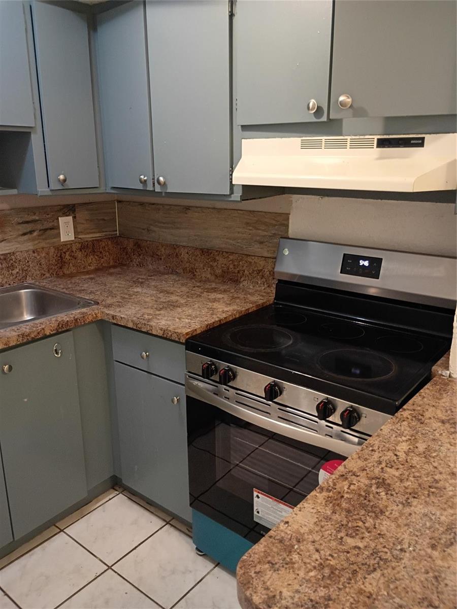 A kitchen features blue cabinets, brown laminate countertops, a stainless steel stove, and white flooring — 1845 NW 55th Avenue, Lauderhill FL 33313, LAUDERHILL, FL