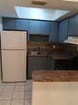 A kitchen features dark cabinets, a white refrigerator, a tiled floor, and a skylight — 1845 NW 55th Avenue, Lauderhill FL 33313, LAUDERHILL, FL