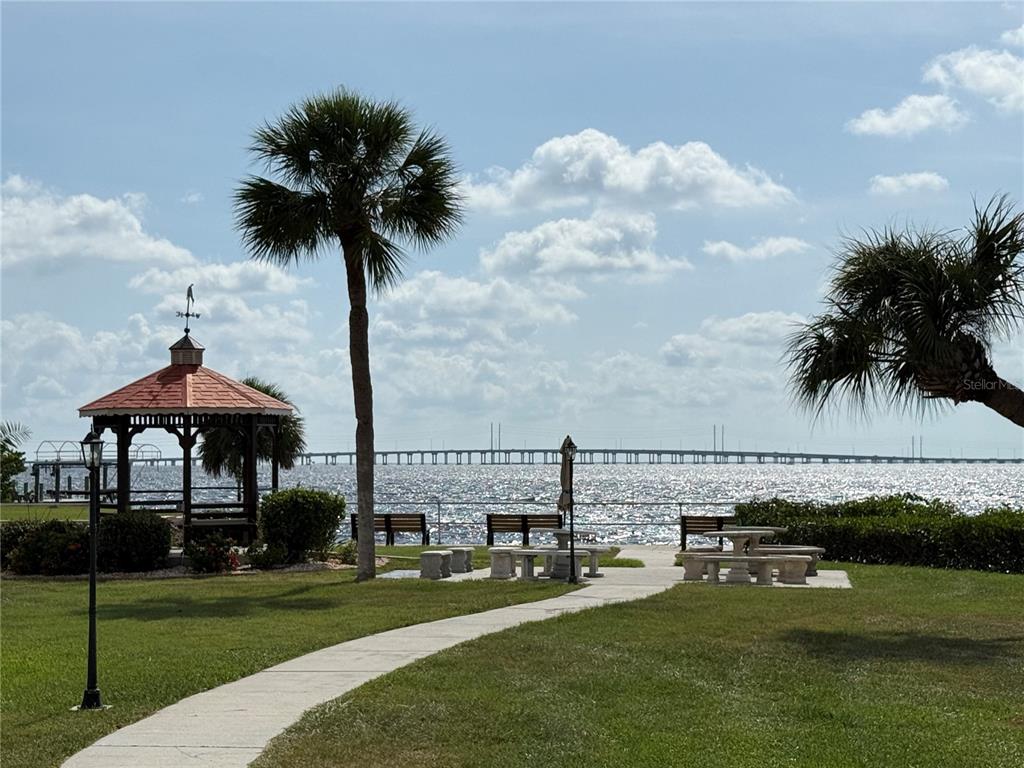 A waterfront park features a gazebo, palm trees, picnic tables, and a long bridge — 25188 MARION AVENUE UNIT 1027, PUNTA GORDA, FL