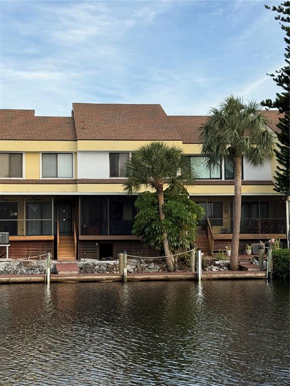 A multi-story waterfront townhouse with a screened-in lower level and a wooden dock — 25188 MARION AVENUE UNIT 1027, PUNTA GORDA, FL