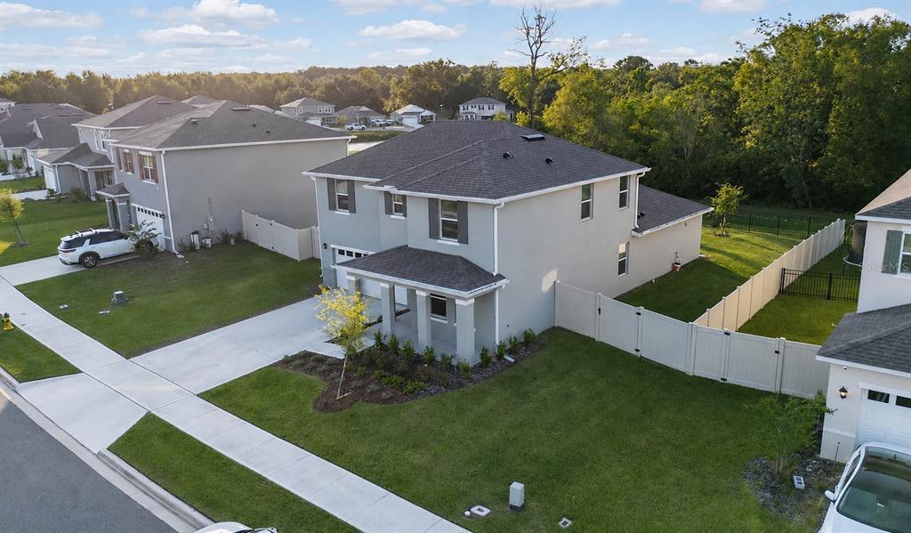 An aerial view of a two-story suburban house with a gray exterior and fenced yard — 5189 GREENHEART AVENUE, MOUNT DORA, FL