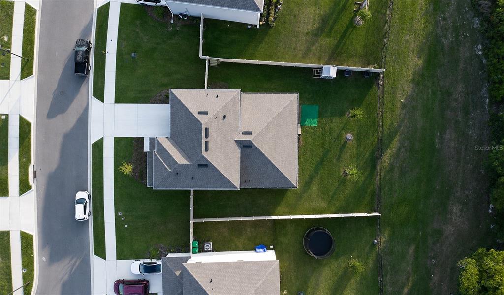 An aerial view shows a house with a gray roof, a fenced backyard, and driveway — 5189 GREENHEART AVENUE, MOUNT DORA, FL