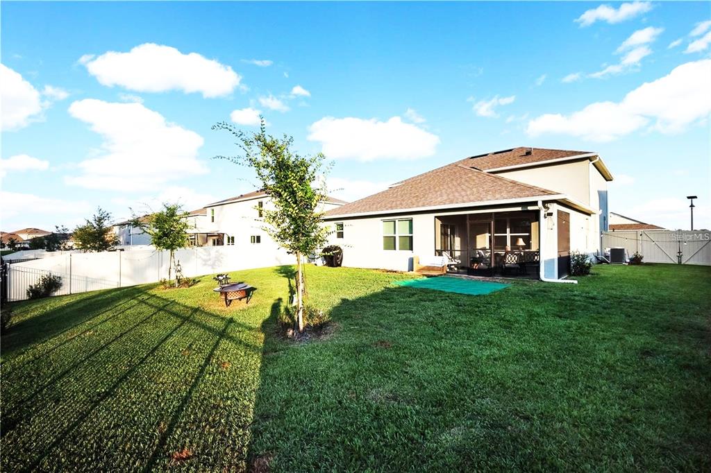 A backyard view of a two-story house with a screened-in patio and green lawn — 5189 GREENHEART AVENUE, MOUNT DORA, FL