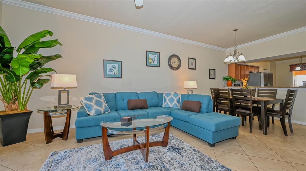 A living room features a blue sectional sofa, glass coffee table, and adjacent dining area — 8105 GRAND ESTUARY TRAIL UNIT 204, BRADENTON, FL