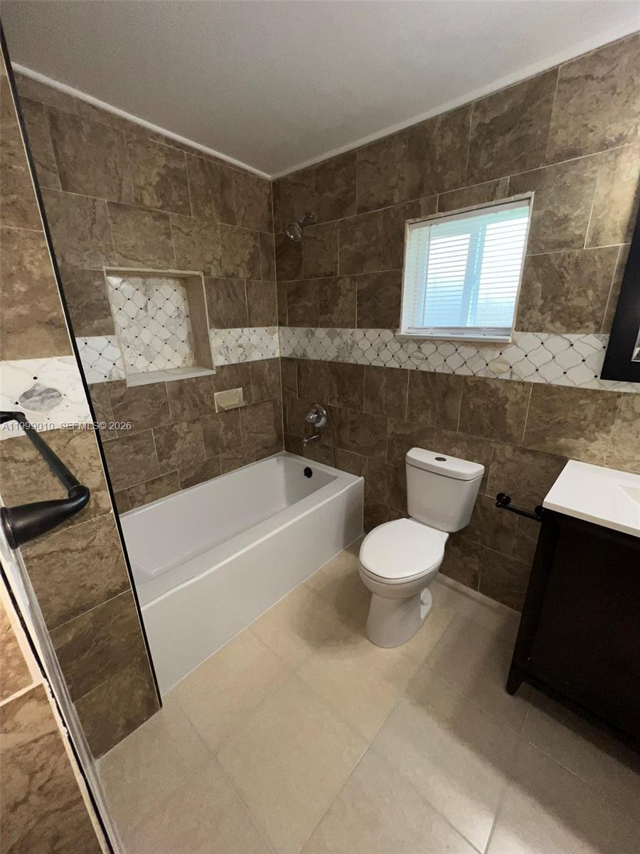 A bathroom features a tiled bathtub, a toilet, and a vanity with brown walls — 6018 Plunkett St # 1, Hollywood FL 33023, HOLLYWOOD, FL