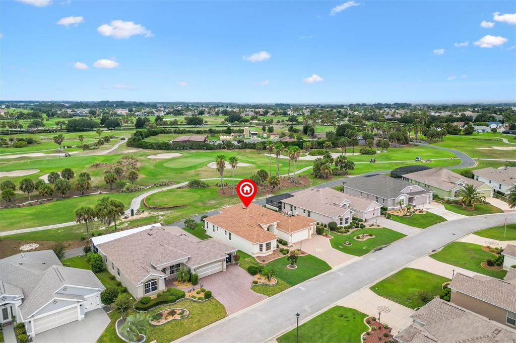 A single-story house with a tan stucco exterior, a brown shingled roof, and a paved driveway — 2757 DAY LILY RUN, THE VILLAGES, FL