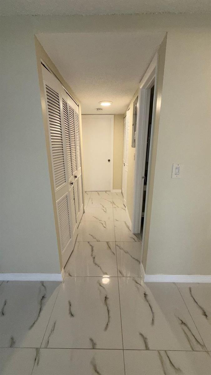 A hallway with white marble-patterned tile flooring, louvered closet doors, and a white end door — 1225 S Flagler Avenue # 313, Pompano Beach FL 33060, POMPANO BEACH, FL