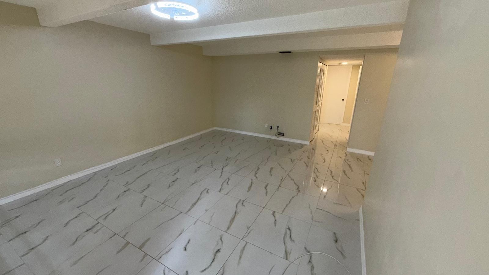 An empty room features beige walls, a white ceiling with beams, and light-colored marble-patterned tile — 1225 S Flagler Avenue # 313, Pompano Beach FL 33060, POMPANO BEACH, FL
