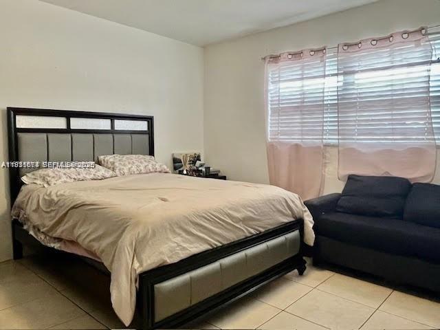 A bedroom features a dark wood bed frame, a beige comforter, and a dark sofa — 12890 NE 8th Ave # 102, North Miami FL 33161, NORTH MIAMI, FL