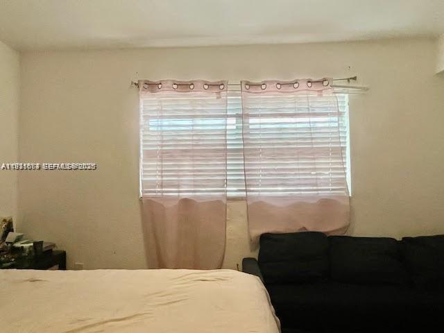 A bedroom features a bed, a dark sofa, and a window with light pink curtains — 12890 NE 8th Ave # 102, North Miami FL 33161, NORTH MIAMI, FL