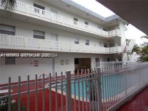 A three-story white apartment building features exterior walkways and a swimming pool in the foreground — 12890 NE 8th Ave # 102, North Miami FL 33161, NORTH MIAMI, FL