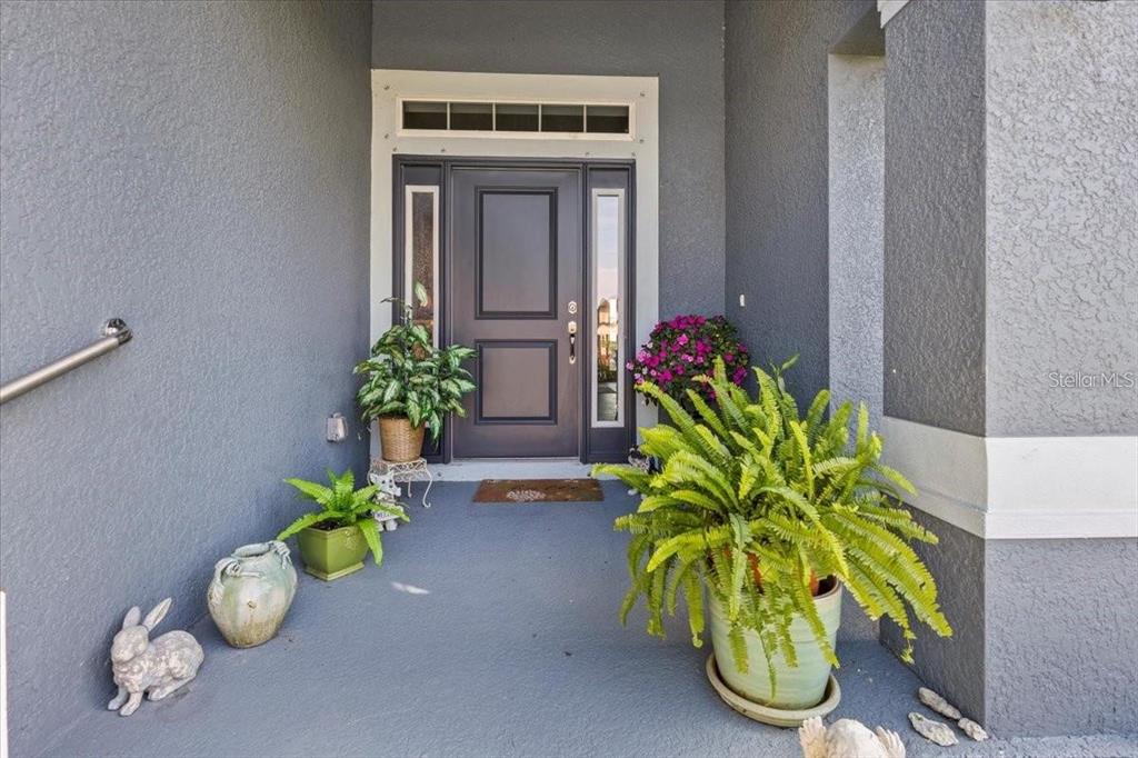 A gray front door with side lights and a transom window on a covered porch — 15251 APPLETON BOULEVARD, PORT CHARLOTTE, FL