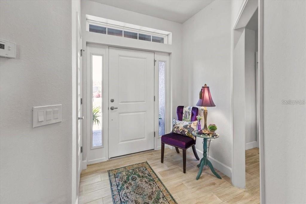 An entryway features a white front door, a purple chair, and a small side table — 15251 APPLETON BOULEVARD, PORT CHARLOTTE, FL