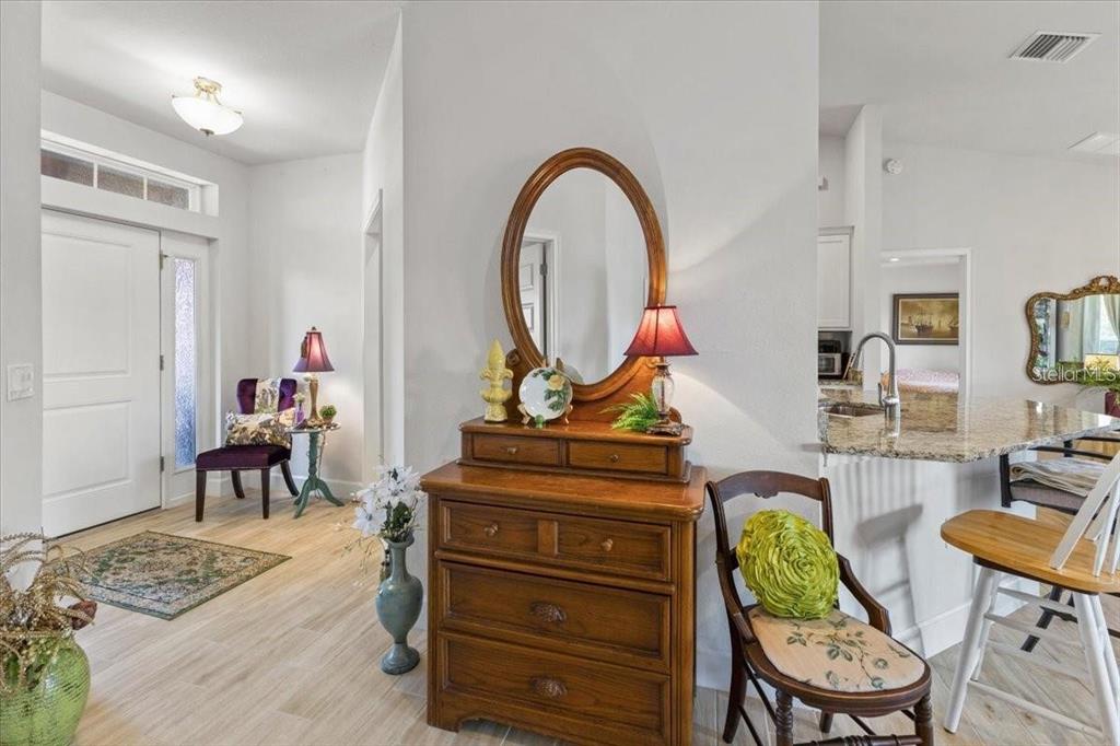A wooden dresser with an oval mirror sits in a foyer next to a kitchen — 15251 APPLETON BOULEVARD, PORT CHARLOTTE, FL