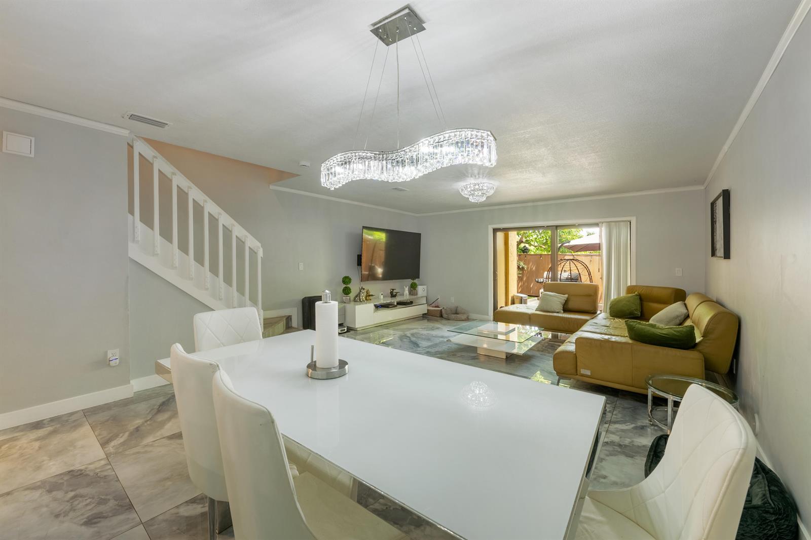 A dining area with a white table and chairs opens into a living room — 1129 NE 210th Terrace # 210, Miami FL 33179, MIAMI, FL