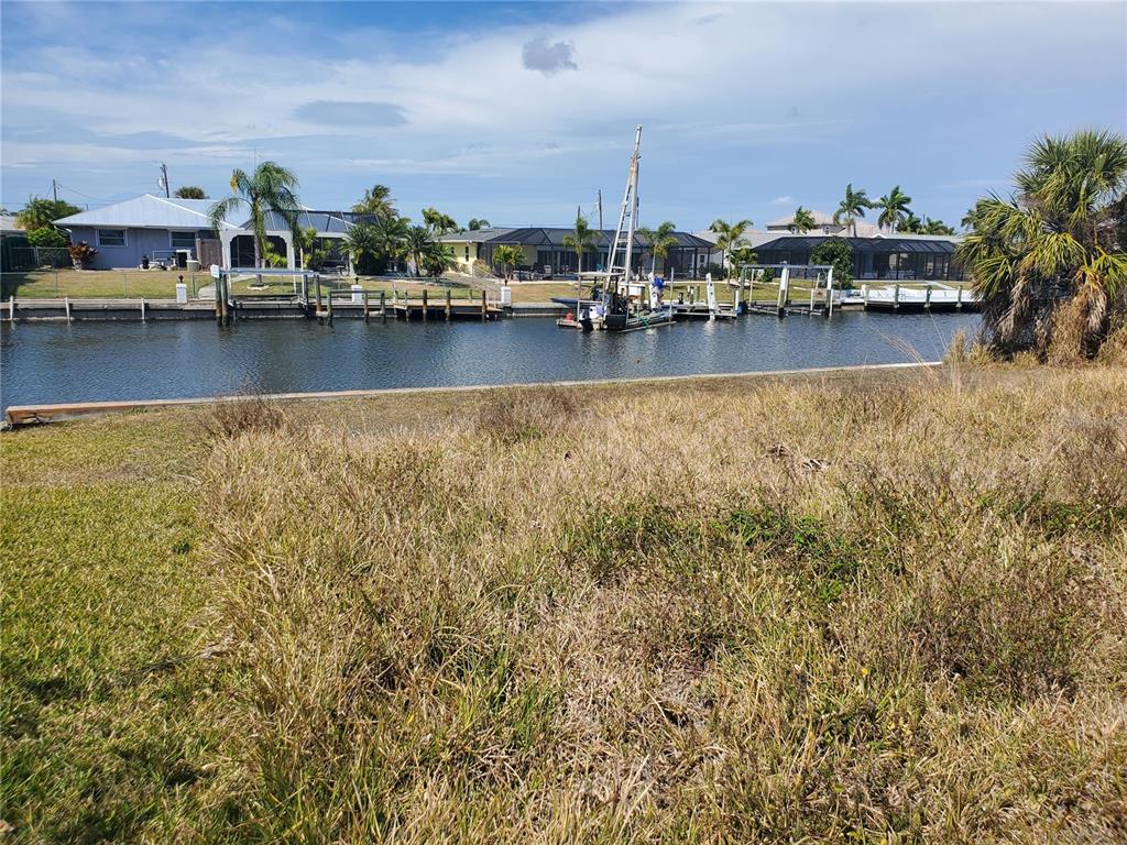 A grassy waterfront lot overlooks a canal with boat docks and residential homes — 5299 EARLY TERRACE, PORT CHARLOTTE, FL