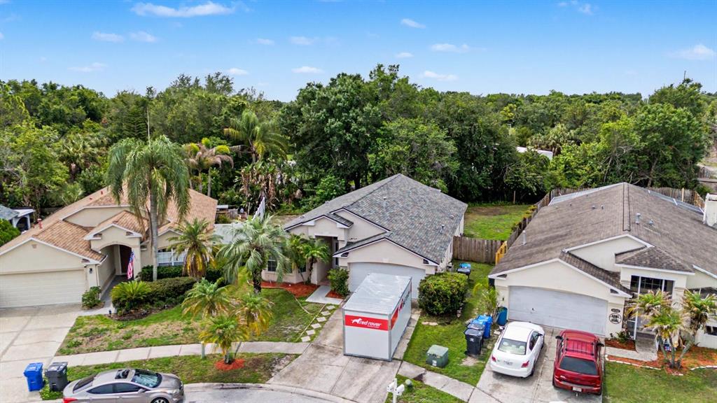 An aerial view shows three suburban houses with driveways and a portable storage container — 10238 CHARLESTON CORNER ROAD, TAMPA, FL