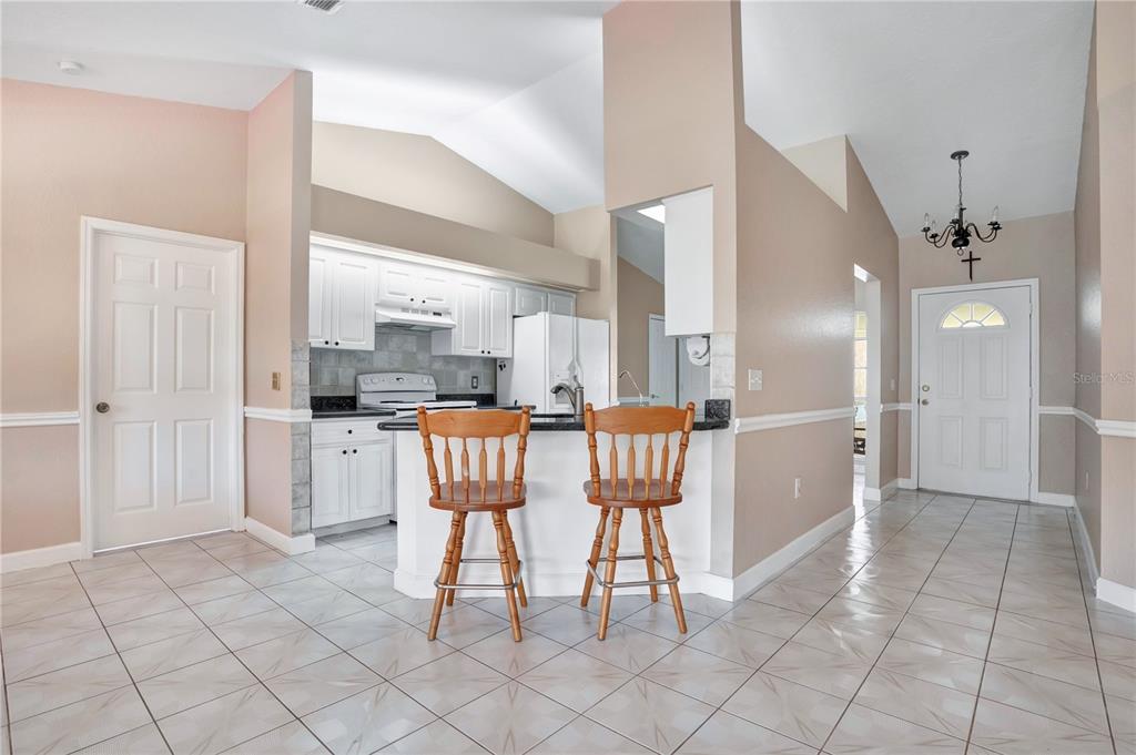 A kitchen with white cabinets and a breakfast bar sits adjacent to an entryway — 667 JESSANDA CIR, LAKELAND, FL