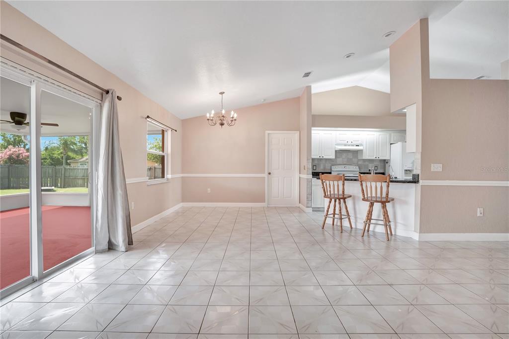 A dining area with tile floors, a chandelier, and a breakfast bar opening to a kitchen — 667 JESSANDA CIR, LAKELAND, FL