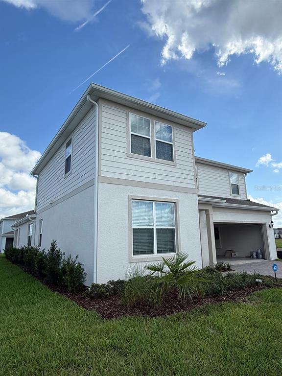 A two-story house with light-colored siding and stucco exterior features a two-car garage — 5555 SETLLINGSTONE LANE, ST CLOUD, FL