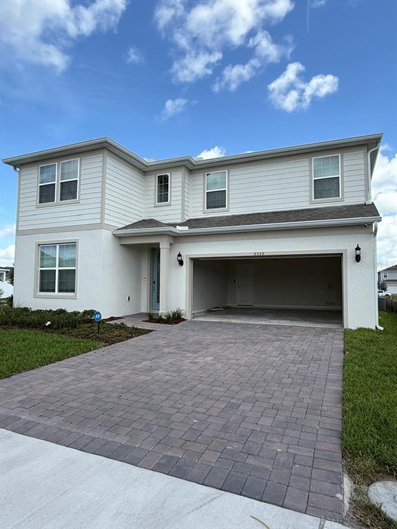 A two-story house with light siding, a paved driveway, and an open two-car garage — 5555 SETLLINGSTONE LANE, ST CLOUD, FL