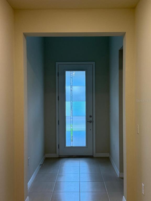 A tiled entryway leads to a white front door with a vertical glass panel — 5555 SETLLINGSTONE LANE, ST CLOUD, FL
