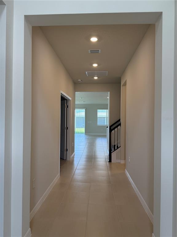 A tiled hallway leads to an open living area with a staircase on the right — 5555 SETLLINGSTONE LANE, ST CLOUD, FL