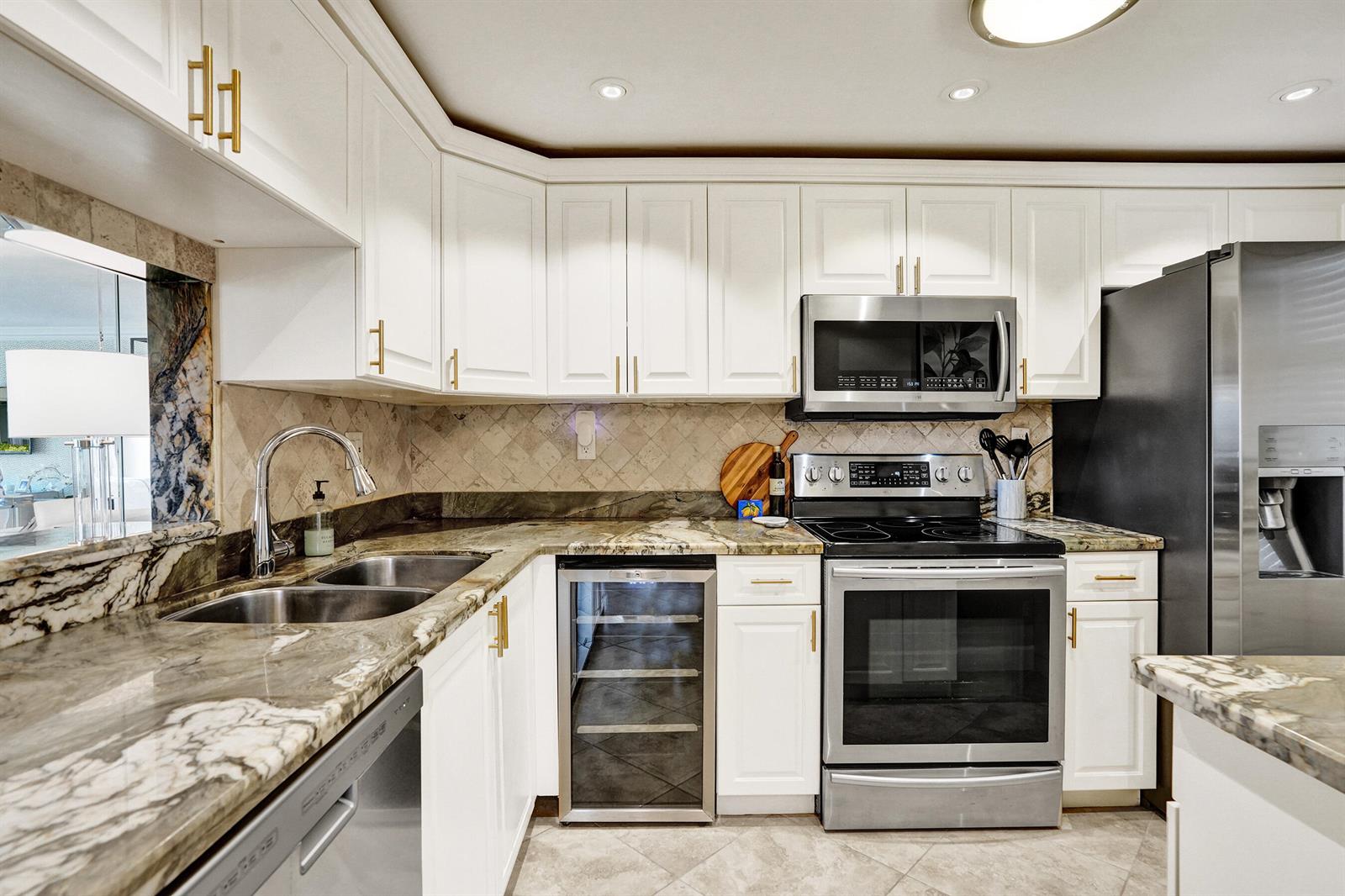 A kitchen features white cabinets, stainless steel appliances, and patterned stone countertops — 801 S Federal Highway # 301, Pompano Beach FL 33062, POMPANO BEACH, FL