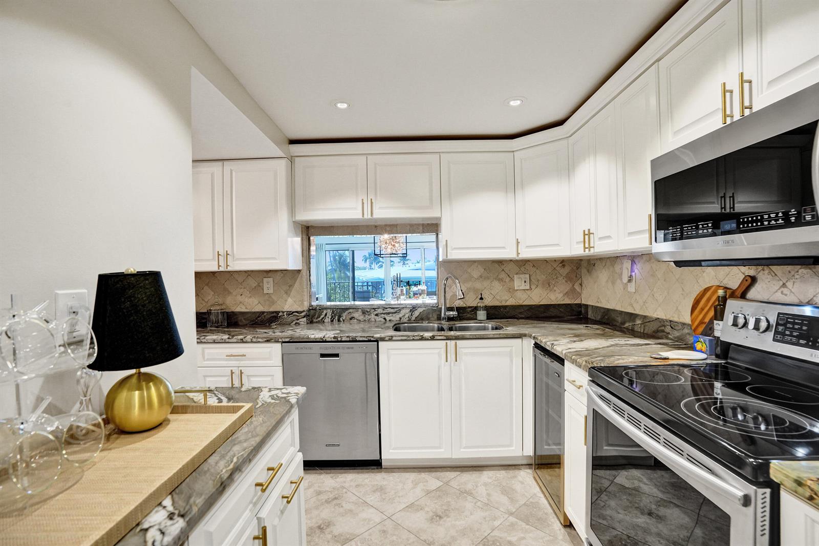 A kitchen features white cabinets, granite countertops, stainless steel appliances, and a window over the sink — 801 S Federal Highway # 301, Pompano Beach FL 33062, POMPANO BEACH, FL