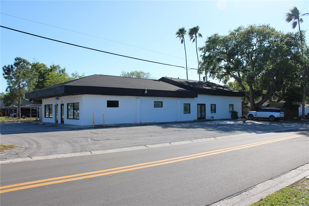 A single-story commercial building with a white exterior and dark roof sits beside a road — 2180 N HERCULES AVENUE, CLEARWATER, FL