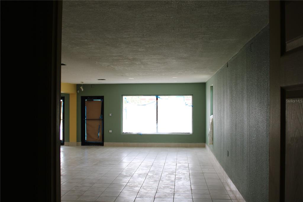 An empty room with light-colored tile flooring, green walls, and a large central window — 2180 N HERCULES AVENUE, CLEARWATER, FL