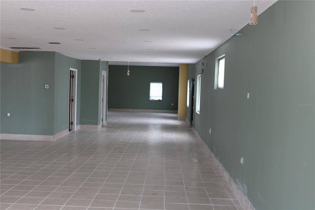 An empty, long room features sage green walls, tiled flooring, and recessed ceiling lighting — 2180 N HERCULES AVENUE, CLEARWATER, FL