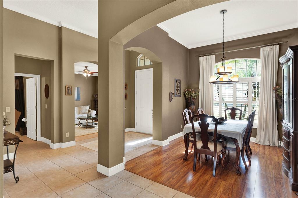 A dining room with wood floors and a chandelier sits adjacent to a tiled entryway — 873 GULF LAND DRIVE, APOPKA, FL