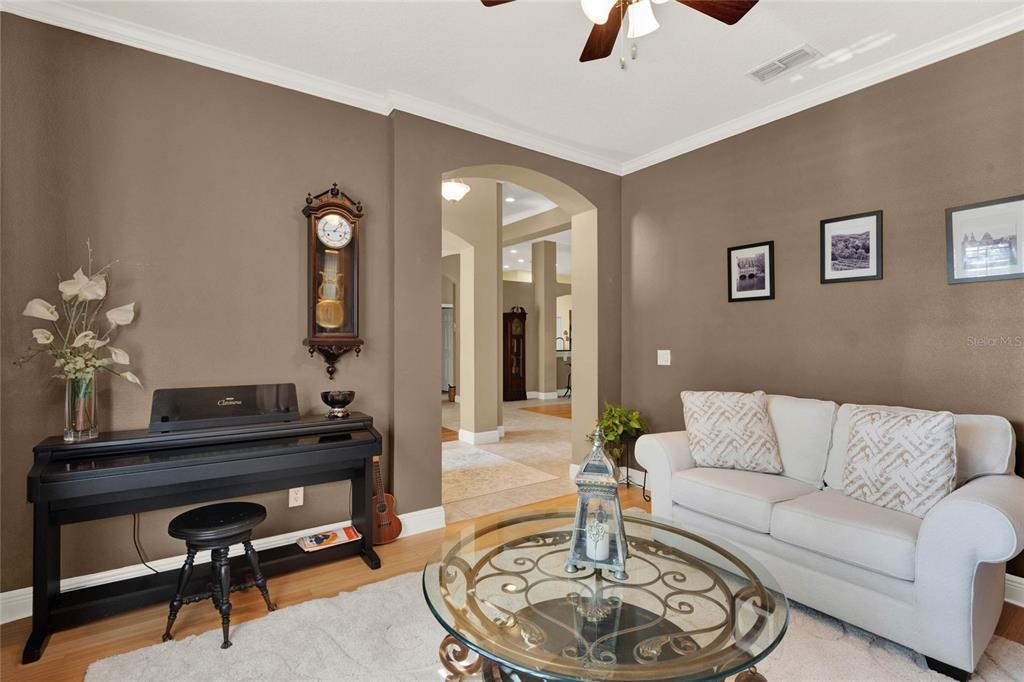 A living room features a piano, a sofa, a coffee table, and a grandfather clock — 873 GULF LAND DRIVE, APOPKA, FL
