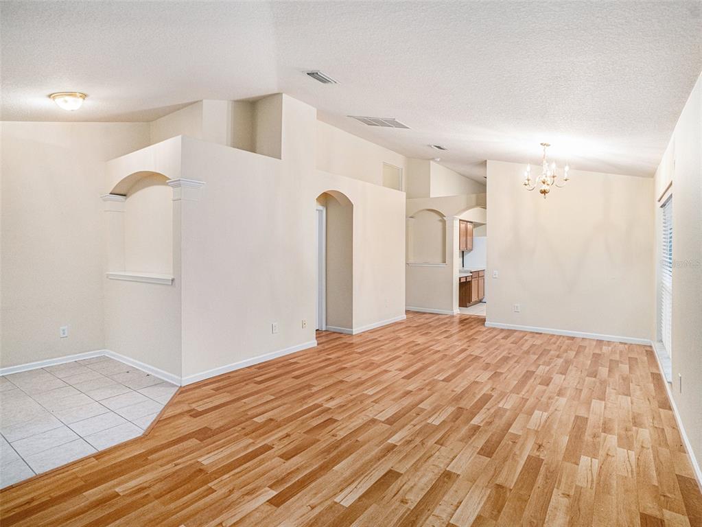 An open-concept living area features light-colored walls, wood-look flooring, arched wall niches, and a chandelier — 11440 MISTY ISLE LANE, RIVERVIEW, FL