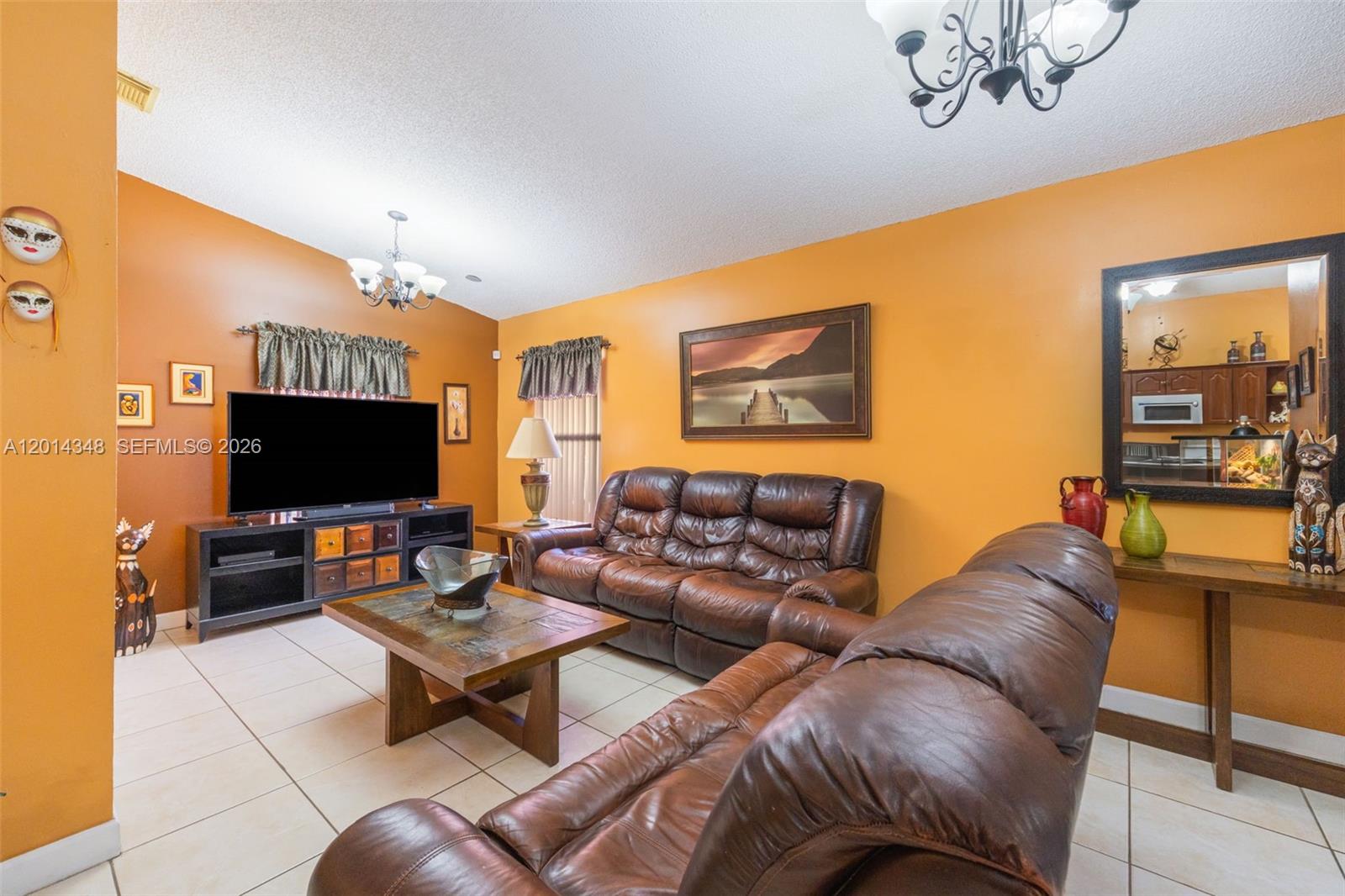 A living room features orange walls, tile flooring, two brown leather sofas, and a television — 12801 SW 248th Ter, Homestead FL 33032, HOMESTEAD, FL