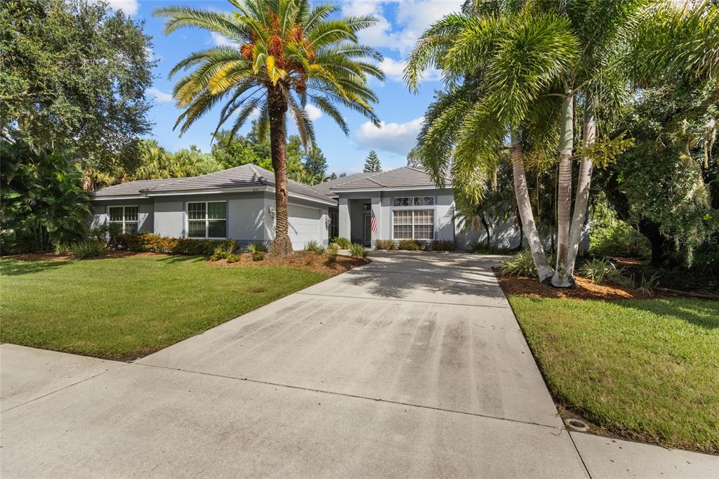 A single-story gray house with a concrete driveway and palm trees in the front yard — 2686 DICK WILSON DRIVE, SARASOTA, FL