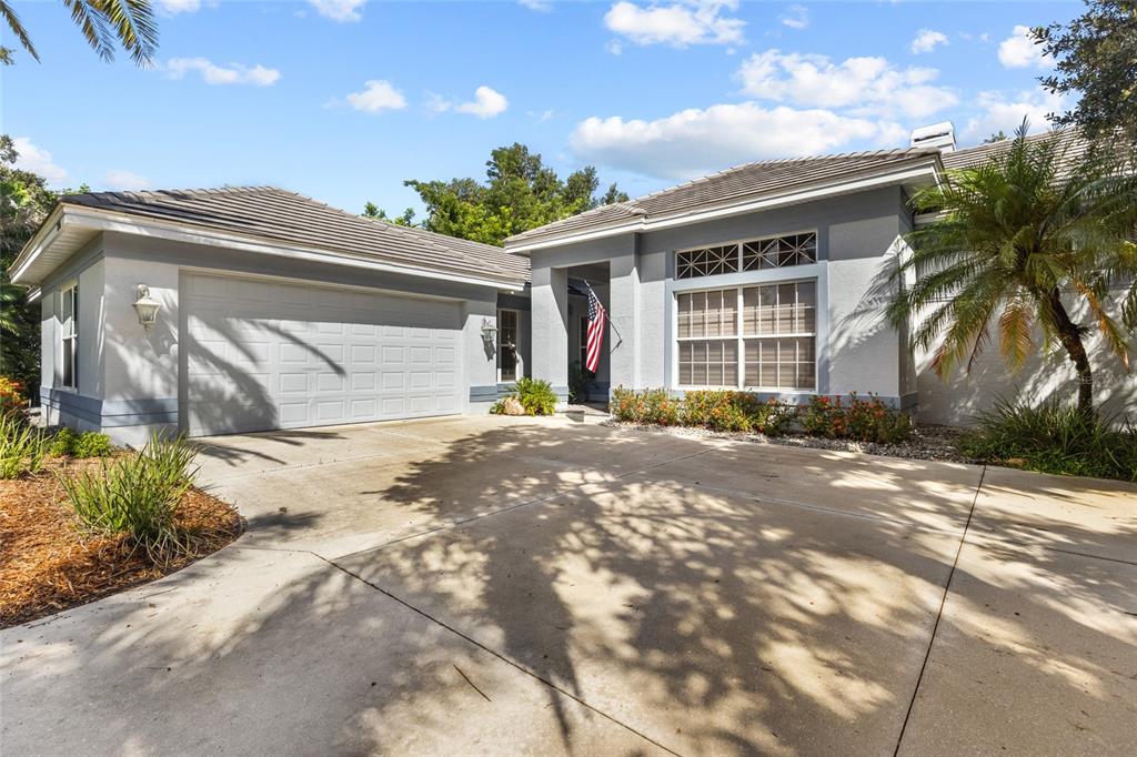 A single-story house with a two-car garage, gray stucco exterior, and a concrete driveway — 2686 DICK WILSON DRIVE, SARASOTA, FL