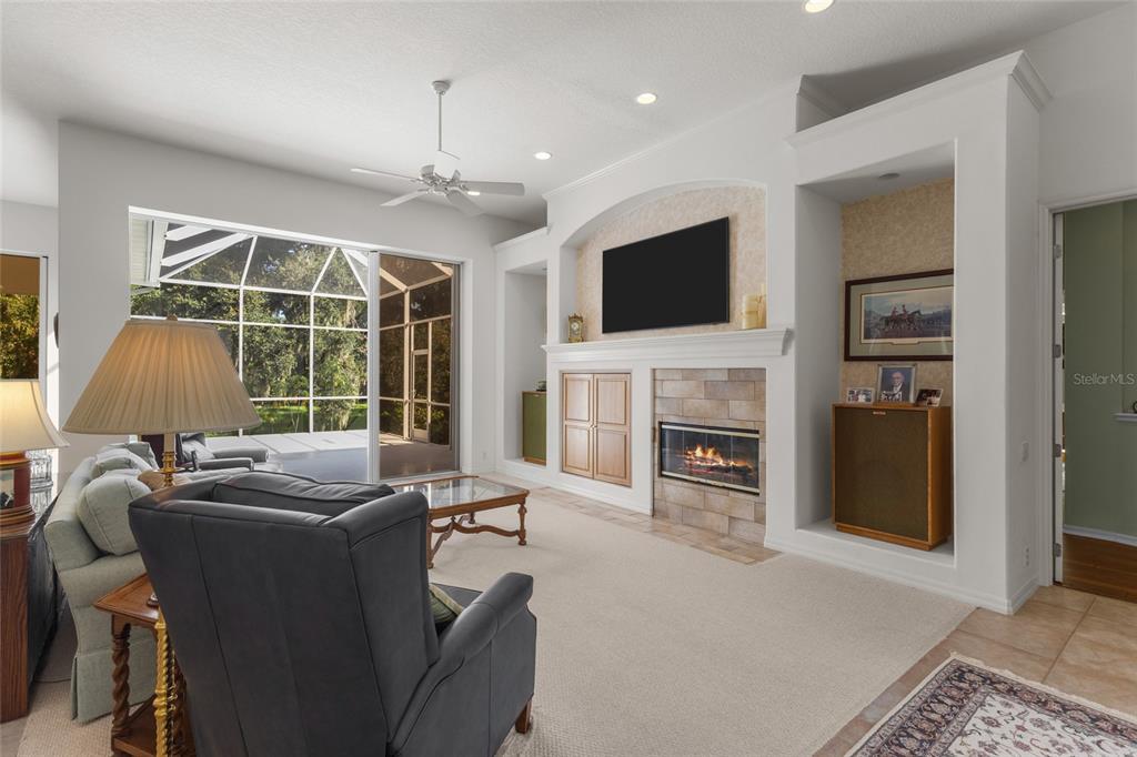 A living room features a fireplace, built-in shelving, a television, and large sliding glass doors — 2686 DICK WILSON DRIVE, SARASOTA, FL