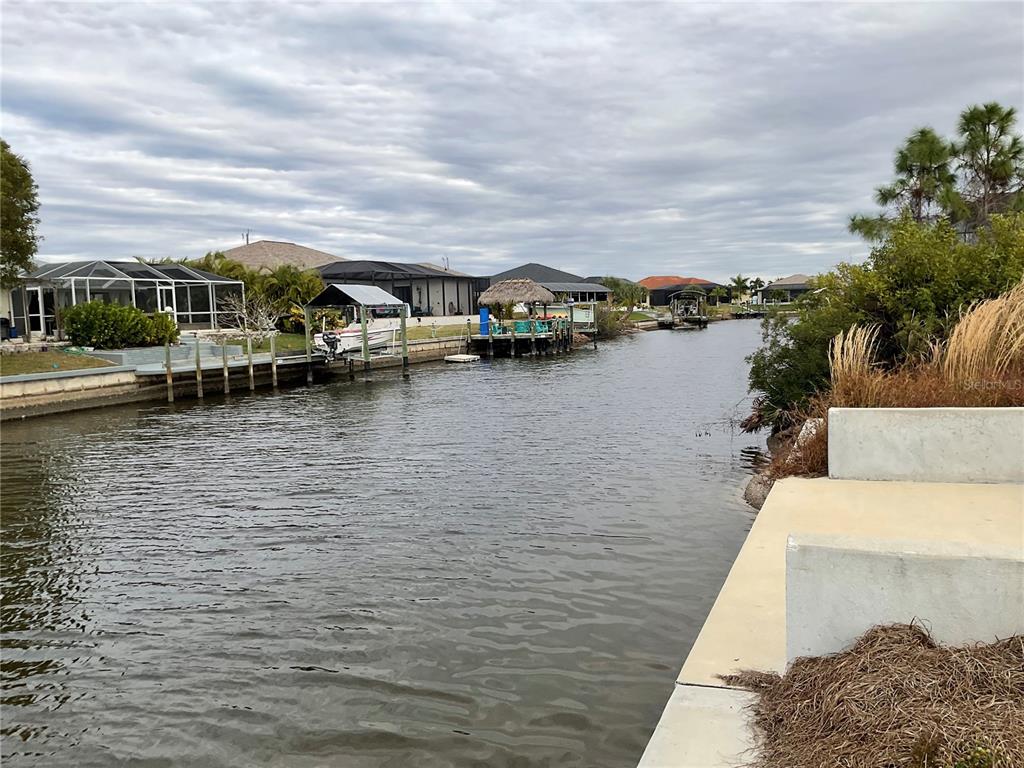 A view of a residential canal with boat docks, houses, and a concrete bulkhead — 3431 NW 17TH LANE, CAPE CORAL, FL
